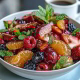 Colorful spring fruit salad featuring oranges, grapefruit, strawberries, and berries, garnished with mint for a refreshing taste.