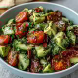 Colorful cucumber tomato avocado salad drizzled with zesty lemon dressing, featuring crisp veggies and smooth avocado for a refreshing bite.  