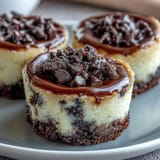 Mini cheesecake bites with Oreo crust, frosted with chocolate and berries.
