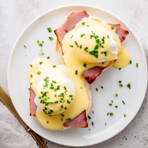 This gourmet Eggs Benedict breakfast features runny yolks, toasted English muffins, and rich hollandaise ready for a weekend brunch.