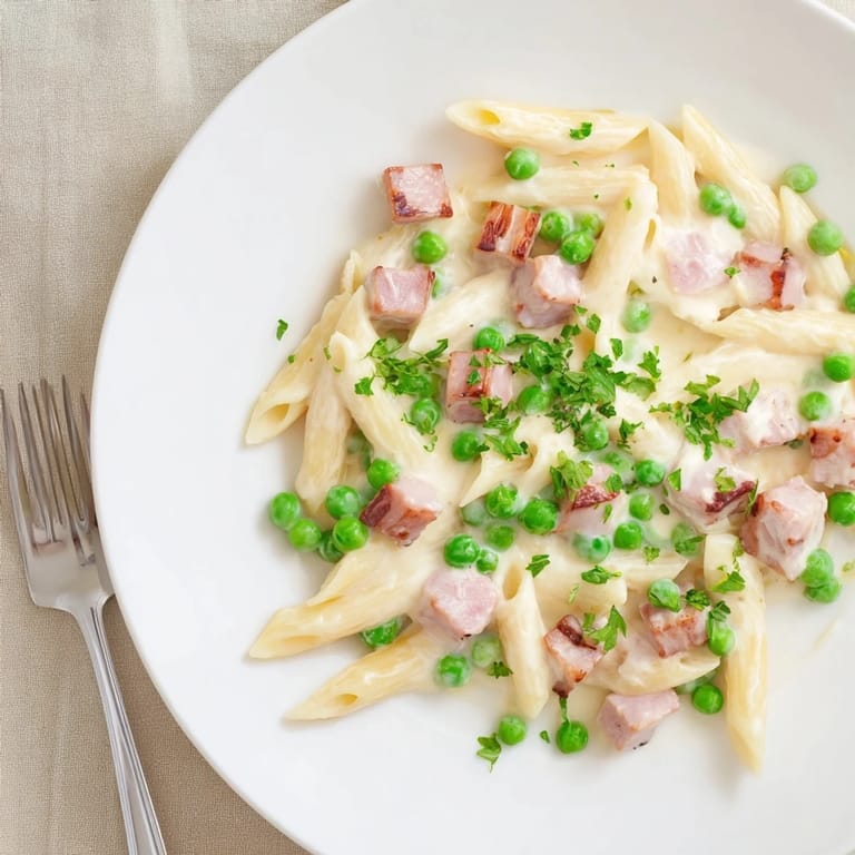 A hearty one-skillet dinner featuring Spring Pea & Ham Pasta, served warm with a glass of crisp white wine.