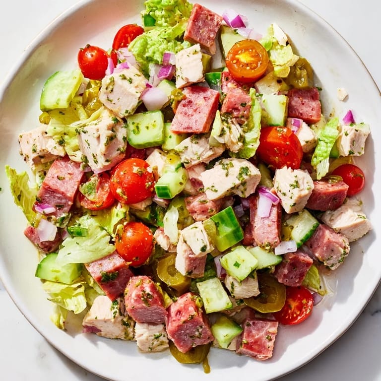 Vibrant, gluten-free Italian Deli Chopped Chicken Salad featuring chopped chicken, salami, and provolone on crisp lettuce, drizzled with a homemade red wine vinegar dressing and garnished with pepperoncini.