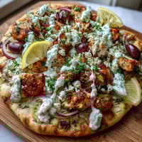 Golden-baked Lemon Feta Chicken Naan Pizza topped with fresh herbs, served on a rustic wooden board.